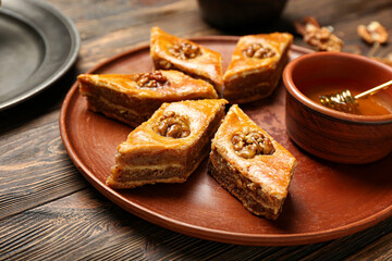 Plate with tasty baklava on wooden background, closeup