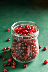 Jar with healthy cranberries on color background