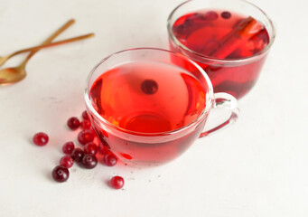 Cups of tasty tea with cranberry on light background