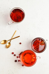 Cups of tasty tea with cranberry on light background