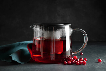 Teapot of tasty tea with cranberry on dark background