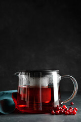 Teapot of tasty tea with cranberry on dark background