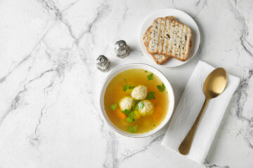 Bowl with tasty meatball soup and bread on light background