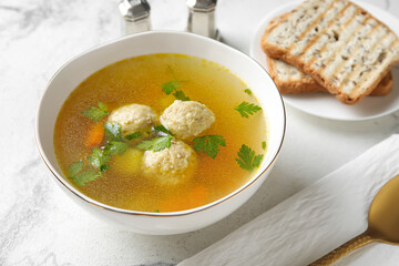 Bowl with tasty meatball soup and bread on light background, closeup