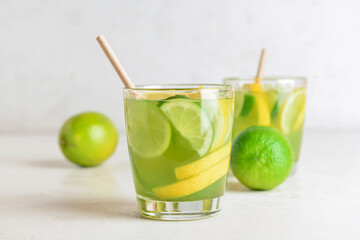Glasses with tasty green lemonade on light background