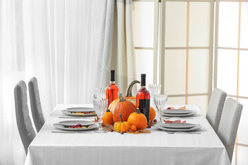 Festive served table with bottles of wine and autumn decor in light room