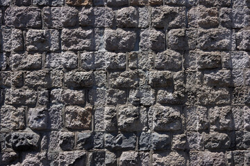 Full frame close-up view of a rough building wall of brocken gray cement stones