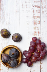Zenith view. Figs and grapes on rustic light-colored boards.