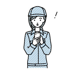 立ってスマートフォンを操作して何かに気づいて驚いた作業員の女性