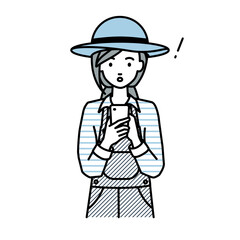 立ってスマートフォンを操作して何かに気づいて驚いた農家の女性