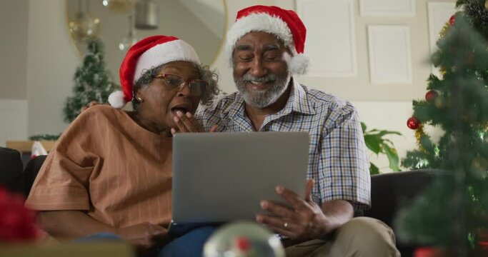 Animation of happy african american senior couple having video call at christmas time