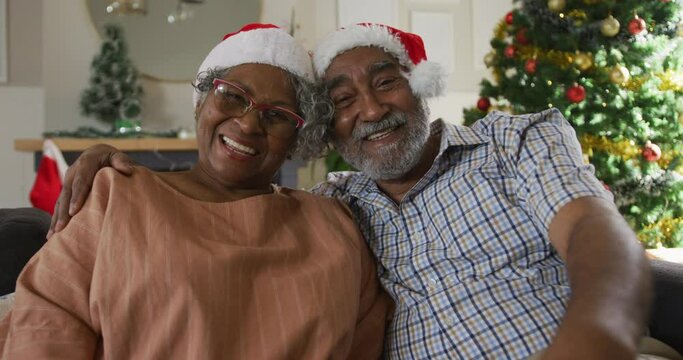Animation of happy african american senior couple having video call at christmas time