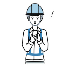 立ってスマートフォンを操作して何かに気づいて驚いた工事現場の女性