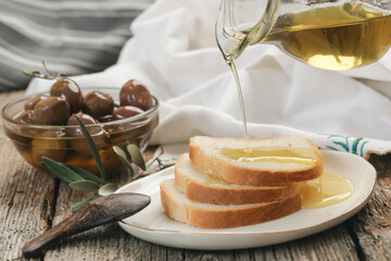 Woman pouring extra virgin olive oil on bread. Homemade helathy snack.	