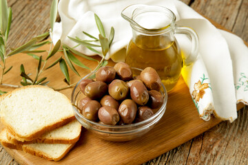 Olives, olive oil and bread on wooden rustic table.