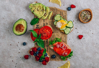 Breakfast Toast Variation with avocado, salmon, egg, cucumber, berries on baking paper