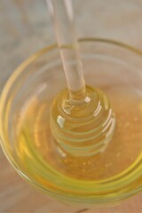 Honey in transparent glass jar with dipper.Glass stick for honey in a glass cup on a wooden table. Organic Fresh honey. 