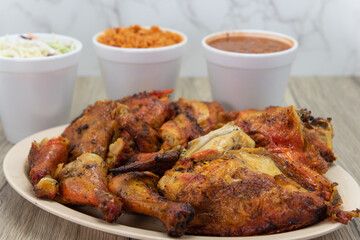 Enormous pile of a full chicken and a half, roasted to perfection, on a plate with Mexican rice, cole slaw, and beans for a family meal