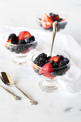 Three glass dessert dishes filled with mixed berries, ready for eating.