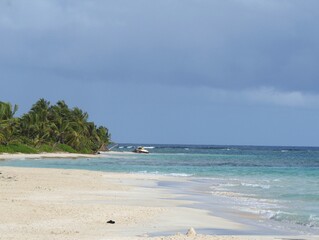Waves rolling into a white sand Flamenco beach in Culebra, Puerto Rico, with an old tanker in the distance.