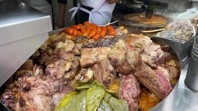 A chef prepares tacos, next to a giant pan full of meat, in a street Tacos stall of downtown Mexico City, Mexico.