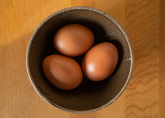Brown Eggs in a Clay Bowl on a Wood Surface
