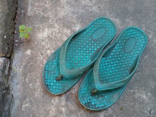 Old and worn rubber sandals. Slippers on the cement floor.