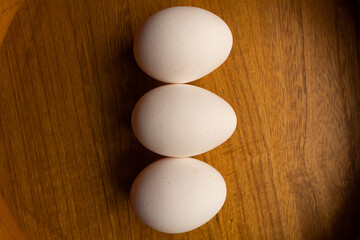 three white eggs on a wooden background
