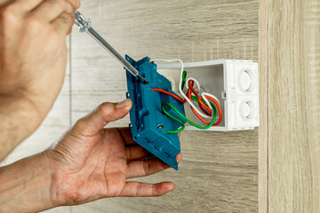 Remove the power electric plug socket from the outlet box on the wooden wall to check the voltage with a screwdriver.