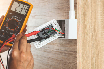 Remove the power electric plug socket from the outlet box on the wooden wall to measure the voltage...