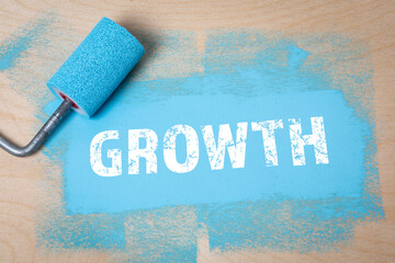 GROWTH. Blue color and paint roller on a wooden background