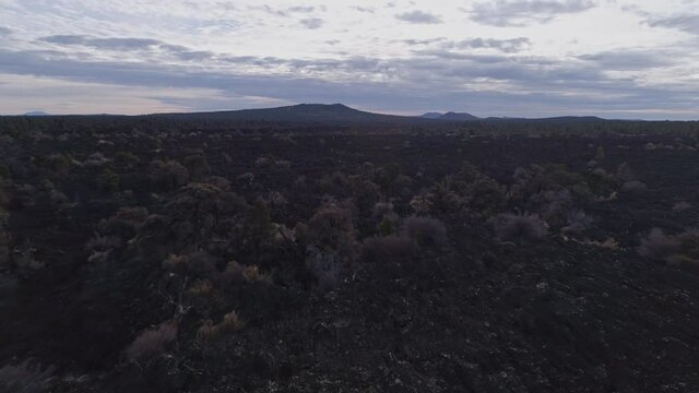 Aerial passing by man looking out over Zuni-Bandera Volcanic lava field, 4K