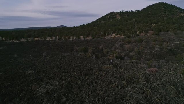 Aerial orbiting man standing in Zuni-Bandera Volcanic Lava Field, 4K