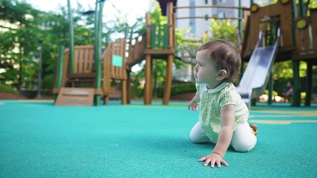 Curious Baby Girl Crawl And Picks Up A Small Stone from Ground Of Playground and Say Something to Mom. - full body, slomo