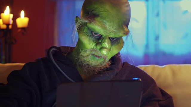Green monster using iPad sitting on couch, close-up