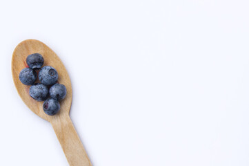 Flat lay of recycled spoon and juicy, fresh blueberries on color table. Space for text. Isolated ripe sweet bilberry fruits in eco spoon on white background. Copy Space. Healthy raw vegetarian food 