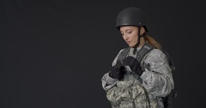 Mature female soldier with gun on black background