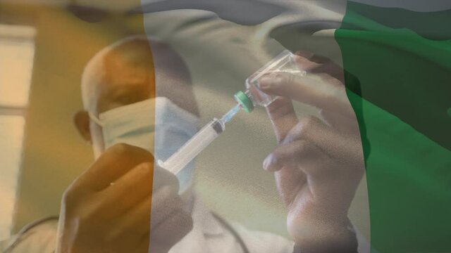 Animation Of Flag Of Ivory Coast Waving Over Doctor Wearing Face Mask And Holding Vaccine