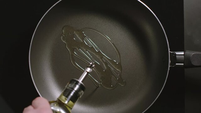 TOP VIEW: Man pouring cooking oil on the frying pan