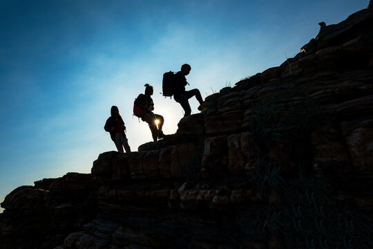 Hikers walking with backpack on a mountain at sunset. traveler going camping. travel concept.