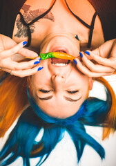 woman with painted blue and orange hair, holding chilli