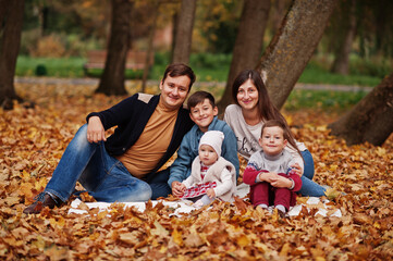 Fototapeta premium Happy family at autumn leaves park. Three kids.