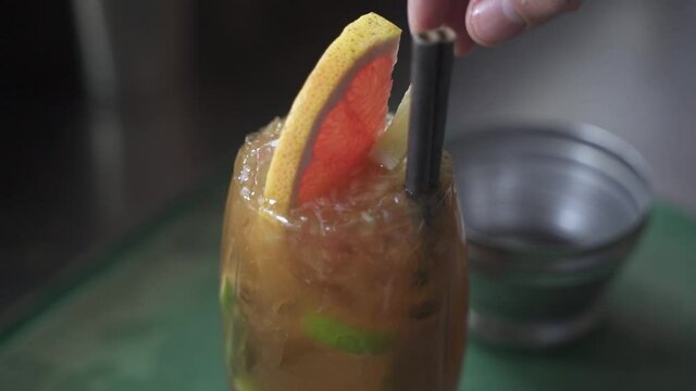 Close up of Bartender adding pomelo fruit into alcoholic Cynar Drink at party,slow motion	