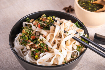 Spicy rice noodles in a bowl with chopsticks, close-up