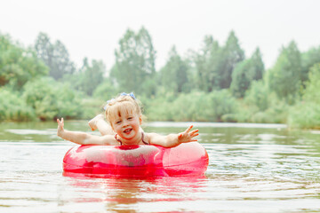 a child swims in the river in an inflatable circle