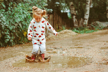 a child runs through puddles in rubber boots