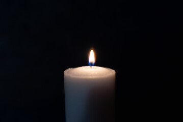 One single light candle burning brightly in the black background.Spiritual candle yellow flame. Flame of candle in the darkness.Copy space.