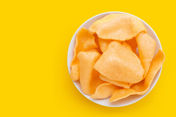 Prawn crackers in white plate on yellow background. Shrimp crispy rice snack