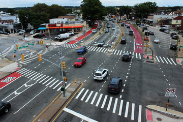 A large regulated intersection of rouds in the borough of Queens, New Yock. View of the roud with cars from above in residential area..
