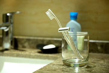 Glass with razor, toothbrush on the table in a bathroom.